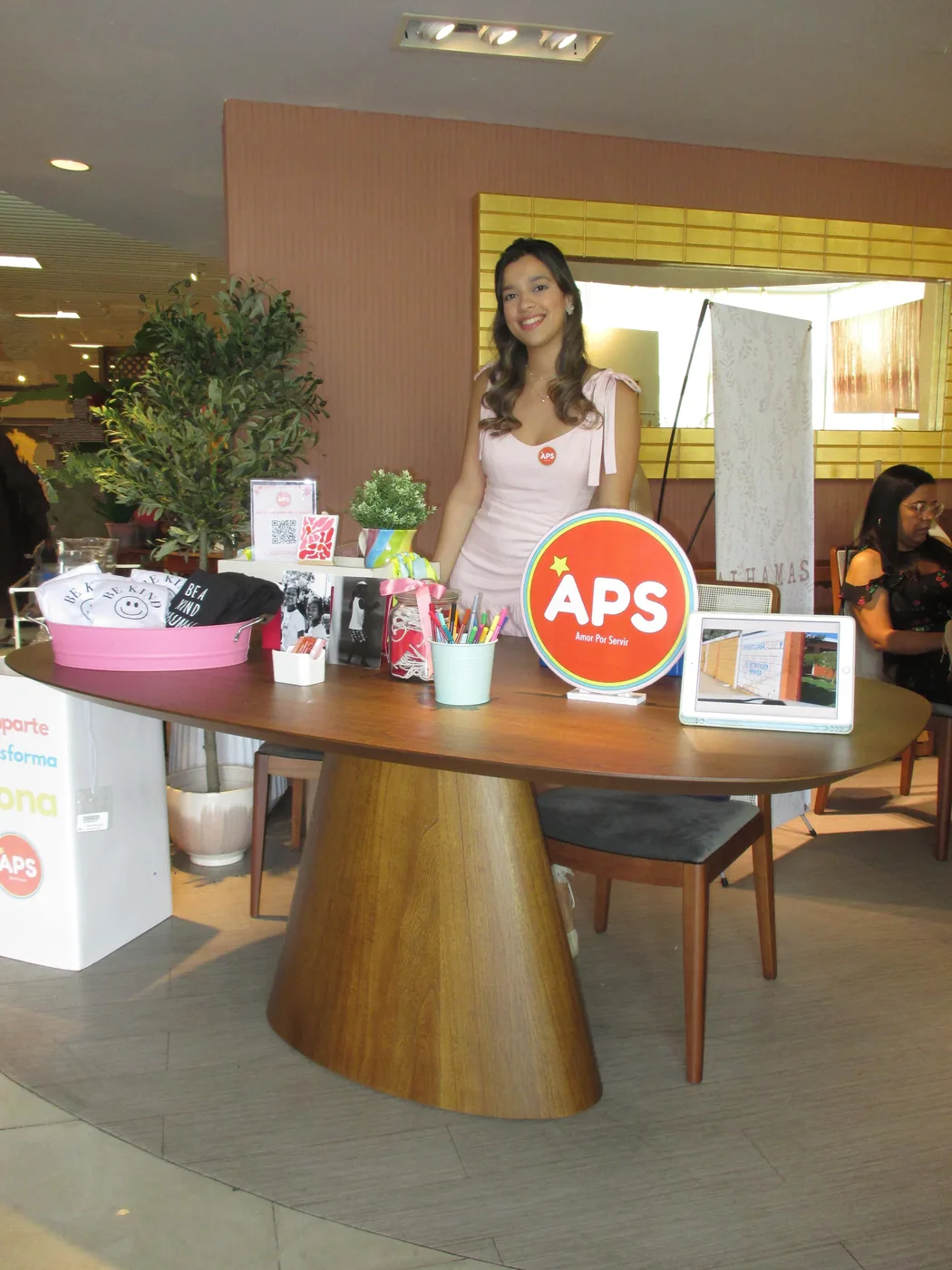 Voluntaria junto a la mesa de productos del bazar