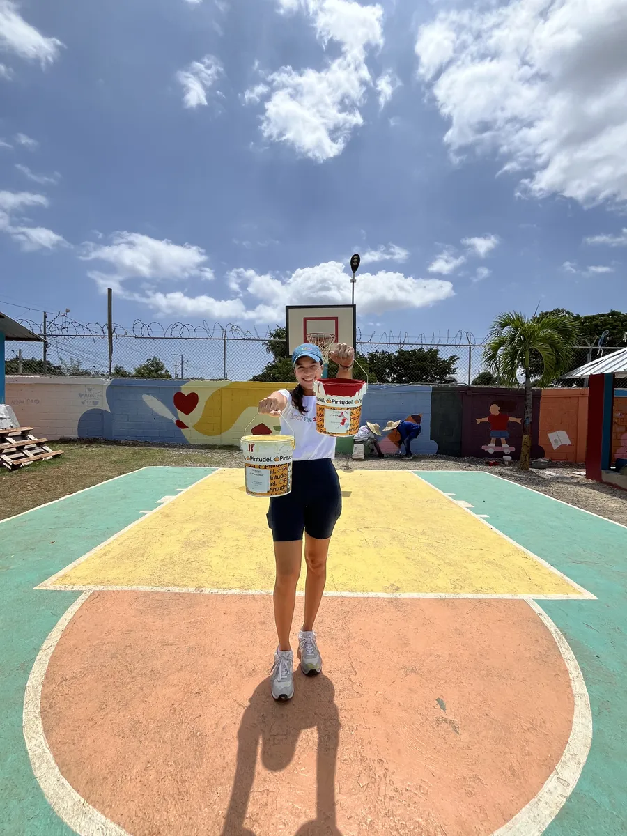 Voluntaria cargando cubetas de pintura sobre la cancha recién pintada