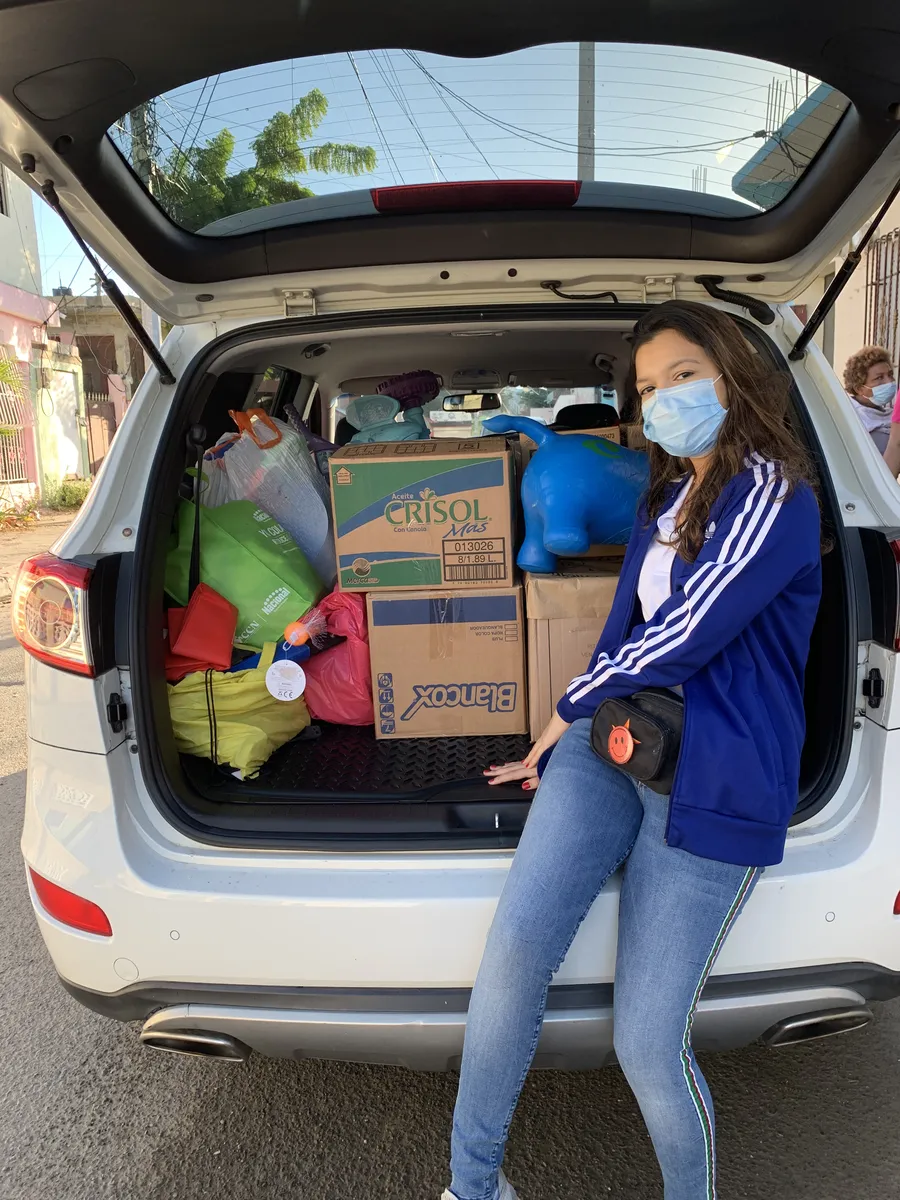 Voluntaria junto al carro cargado de donaciones