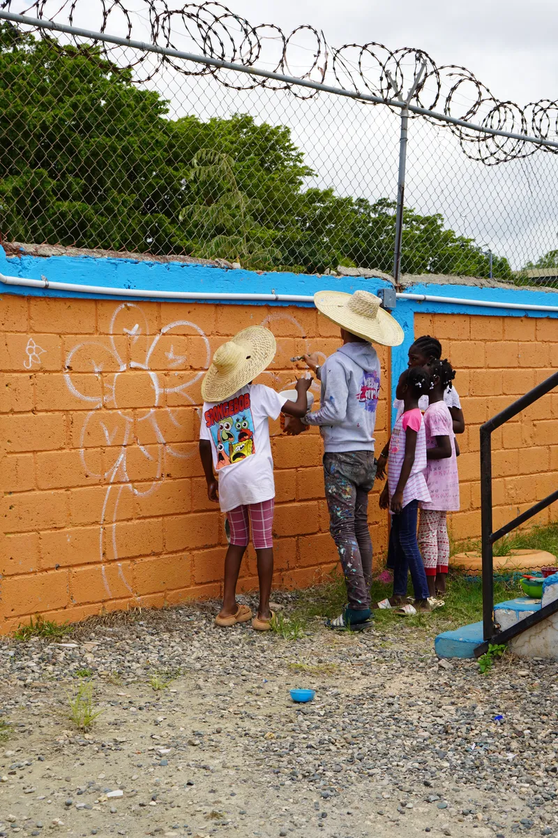 Niños pintando la pared del hogar, de espaldas a la cámara