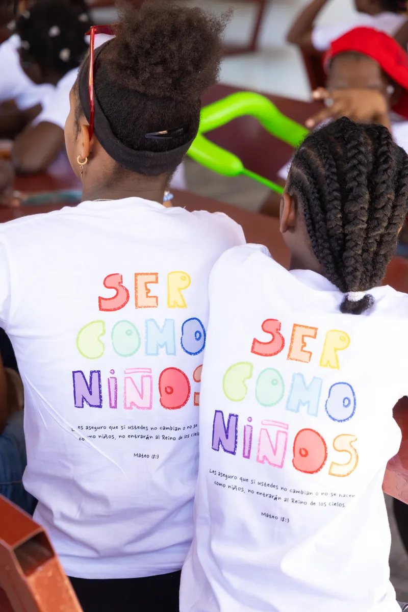 Dos niños de espaldas con las camisetas “Ser como niños”