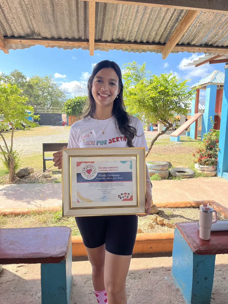 Karla Cantisano sosteniendo el reconocimiento enmarcado de la fundación