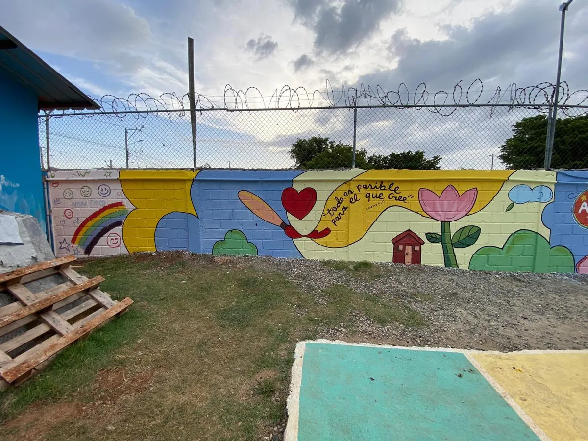 Mural terminado en la pared del hogar, con flores, casas y un arcoíris