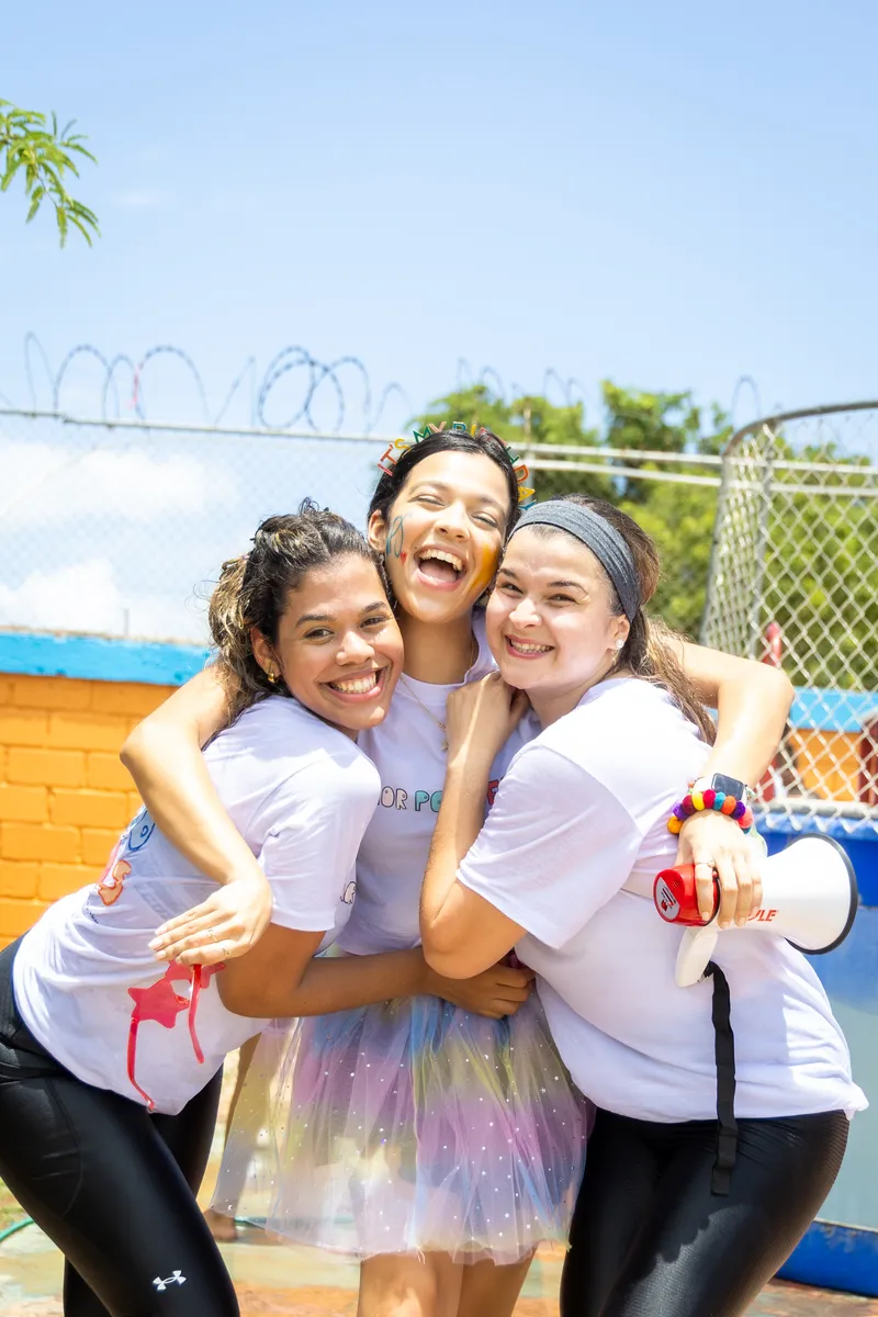Tres voluntarias abrazadas y sonriendo