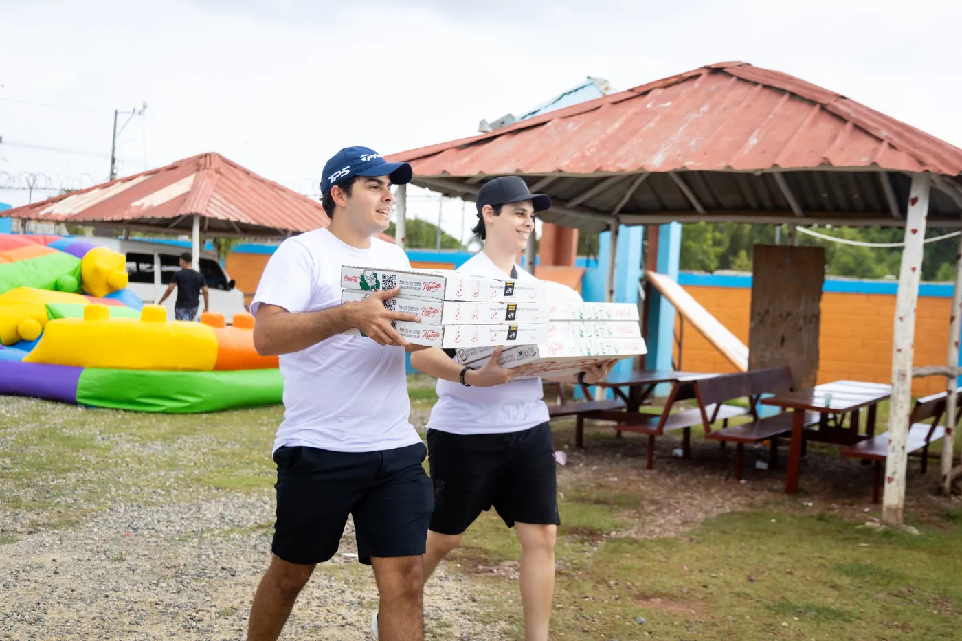 Dos voluntarios cargando cajas de pizza para la actividad
