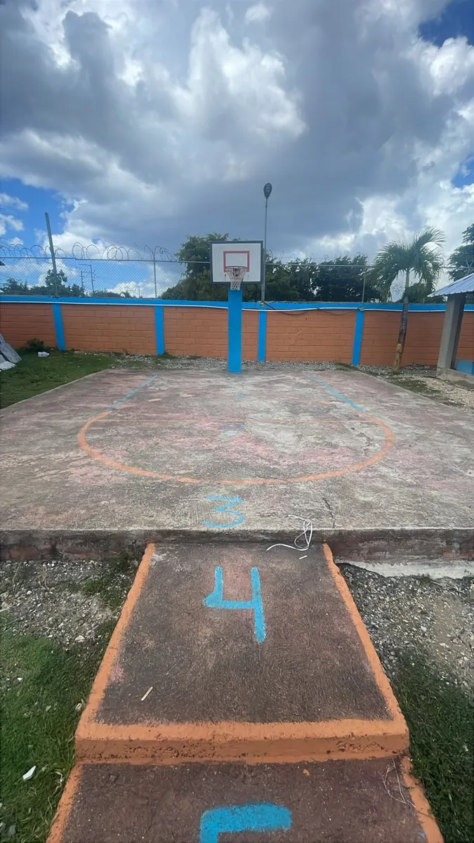 La cancha del hogar antes de la intervención: piso de cemento gris y desgastado